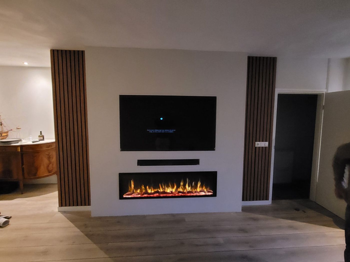 Tv-wand in Ermelo met houten panelen en sfeerhaard, andere hoek