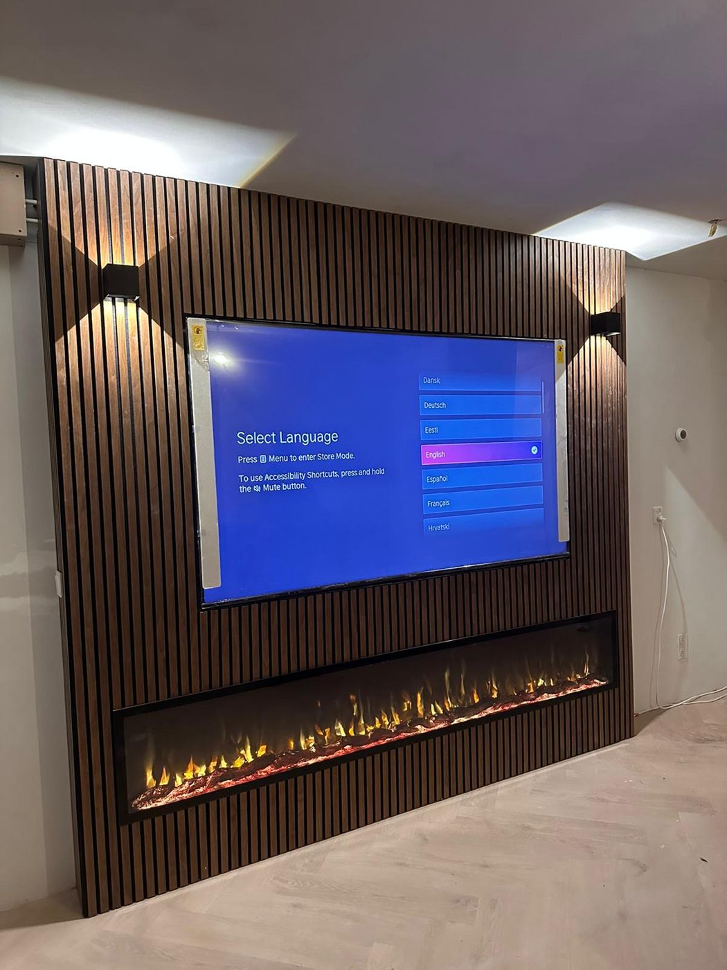 Tv-wand met donkere houten panelen, extra brede sfeerhaard en wandlampen
