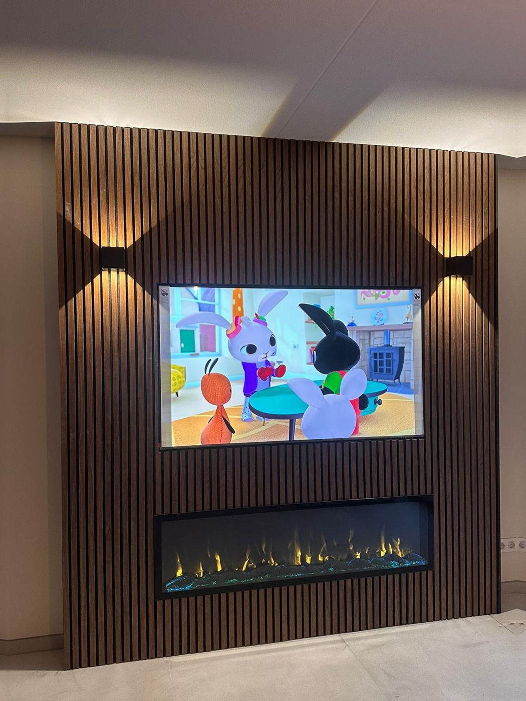 Tv-wand met houten panelen, elektrische sfeerhaard en wandlampen