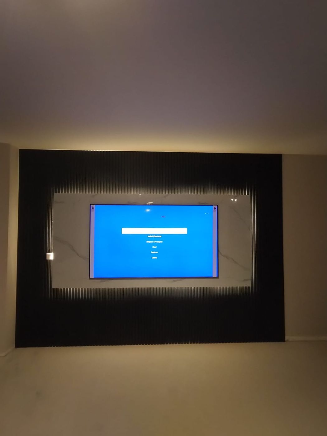 Zwarte wand met houten panelen met een tv-paneel in marmerlook en indirecte LED-verlichting