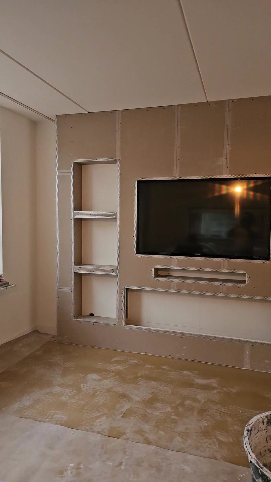 Witte cinewall met sfeerhaard en verlichte nissen in Almere 6 Ruwbouw van de tv-wand in Almere met nissen en planken