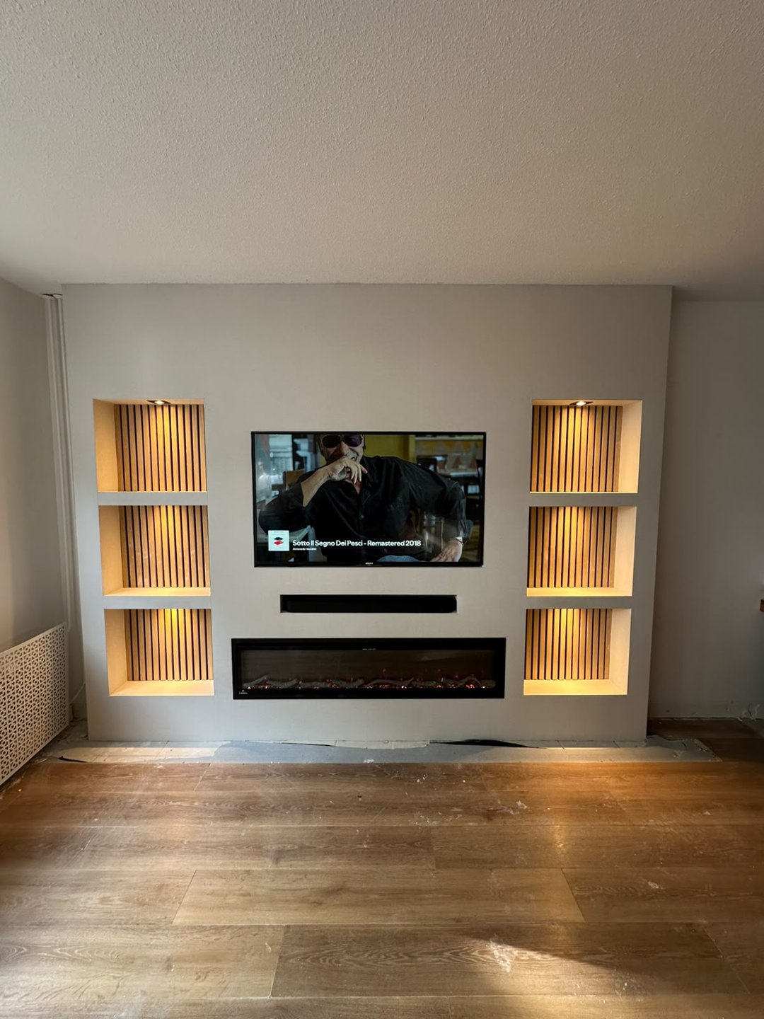 Cinewall met sfeerhaard en verlichte nissen in Diemen 2 Afgewerkte cinewall in Diemen met verlichte nissen, houten panelen en sfeerhaard