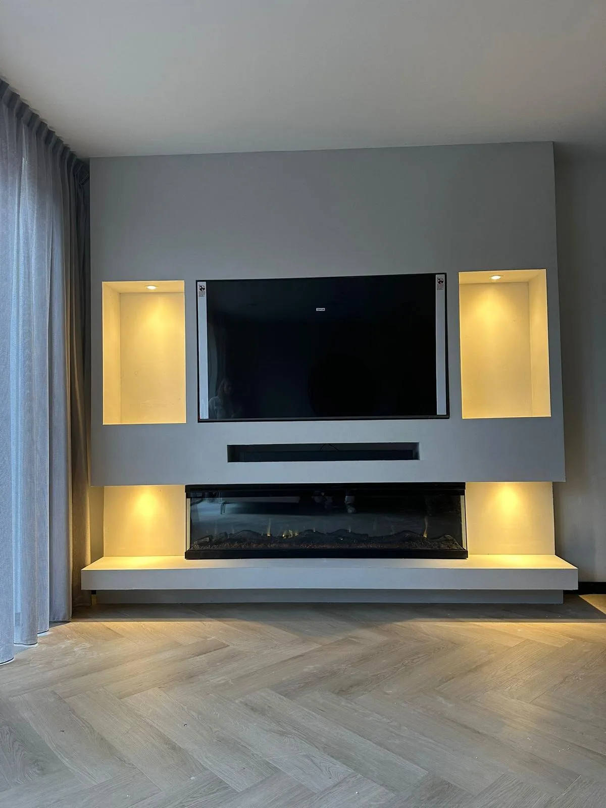 Cinewall met tv, soundbar, sfeerhaard en verlichte nissen aan beide kanten