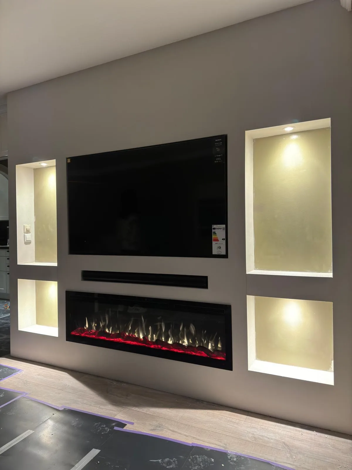 Cinewall met grote tv, soundbar, sfeerhaard en verlichte nis