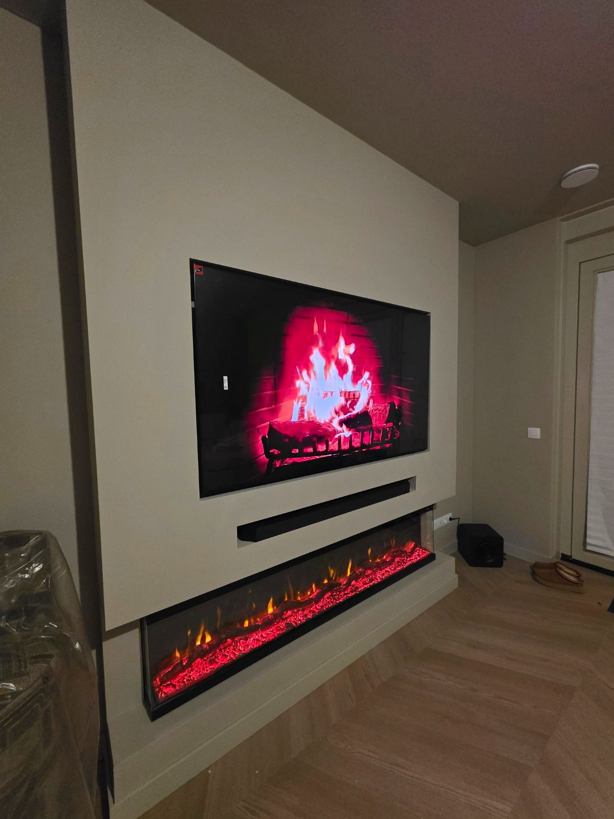 Afgewerkte cinewall met 65 inch tv en 3D-sfeerhaard van 183 cm in Amstelveen 2 Cinewall in Amstelveen van opzij: soundbar-vak en brede sfeerhaard op een verhoogde voet