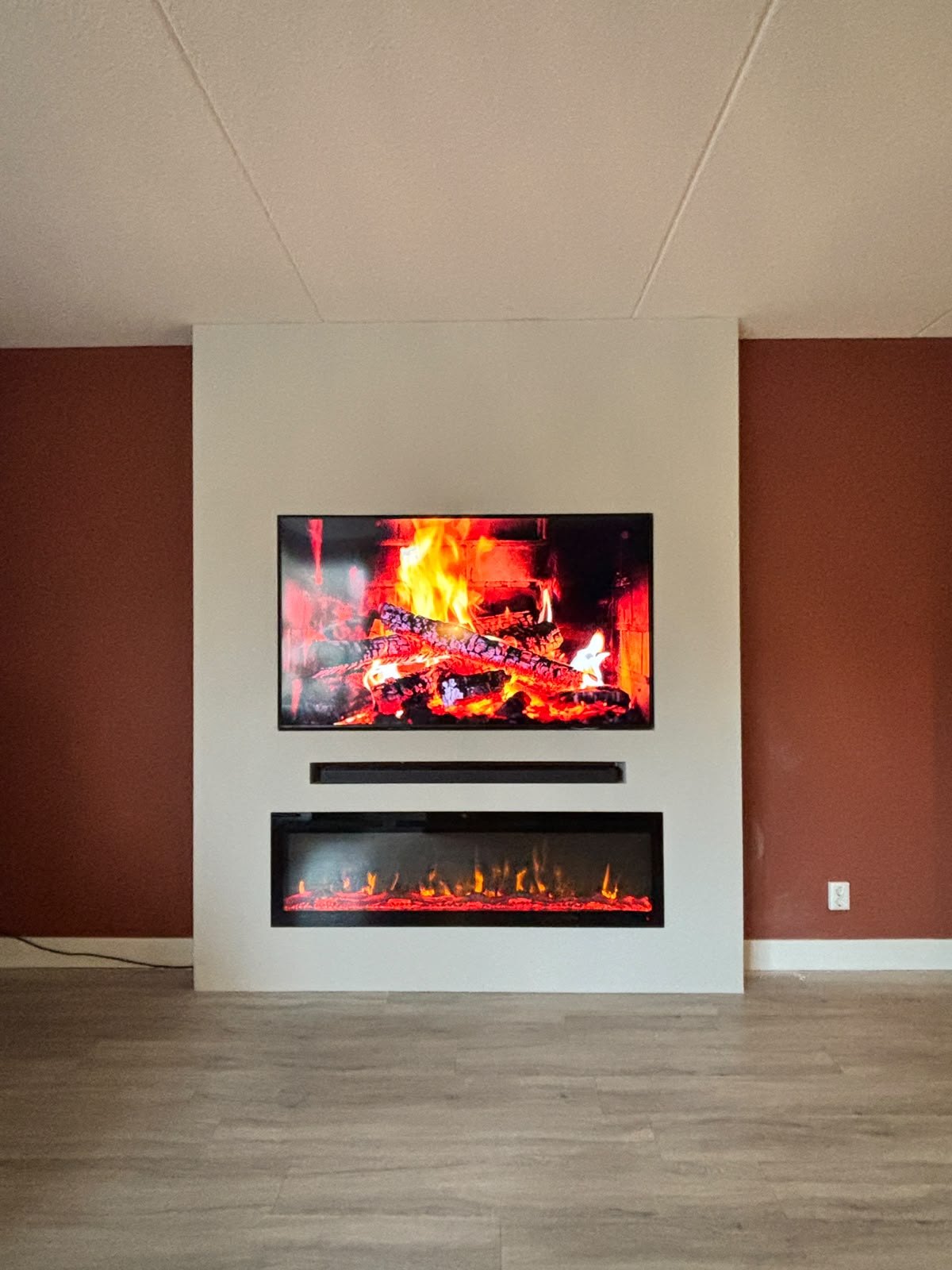 Cinewall met 65 inch tv en sfeerhaard op een wand van 212 cm in Emmeloord 1 Cinewall in Emmeloord met 65 inch tv, soundbar-vak en sfeerhaard van 152 cm
