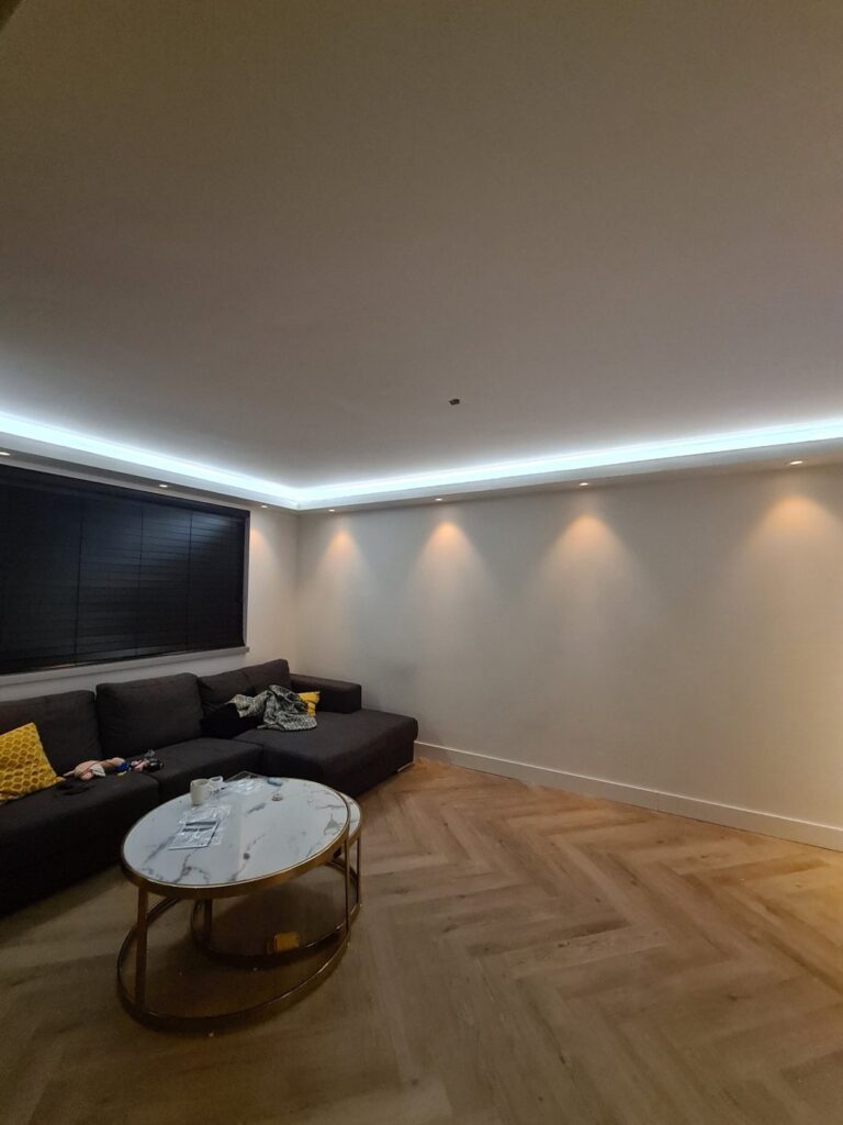 Cinewall met sfeerhaard, verlichte nissen en led-koof in Emmen 3 Plafondkoof met led-strip en inbouwspots langs de woonkamer in Emmen