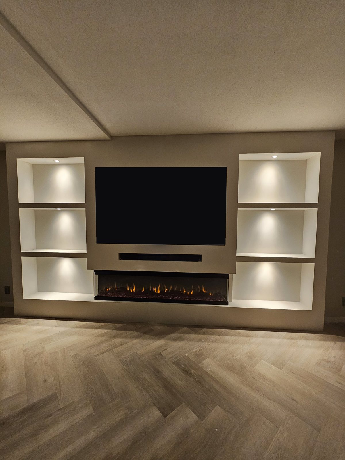 Brede cinewall met tv-nis, soundbar-vak, driezijdige sfeerhaard en zes verlichte nissen in Heerlen