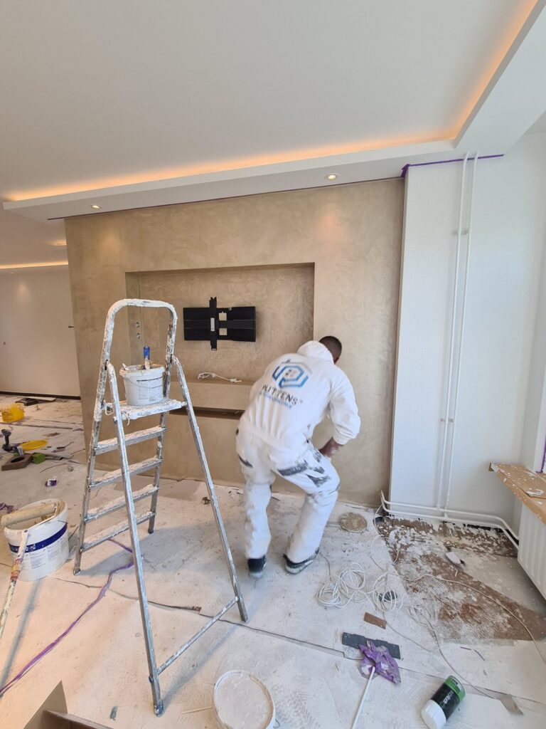Medewerker van Puttens Interieurbedrijf brengt de decoratieve stuclaag aan op de tv-wand in Helmond