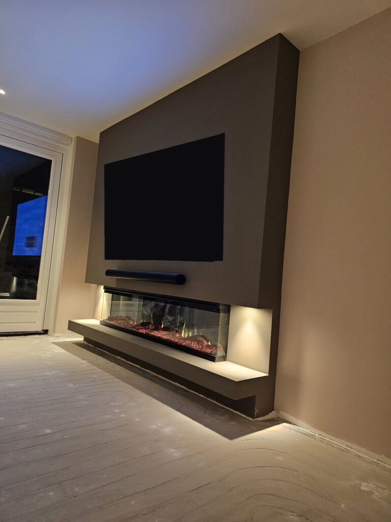 Zijaanzicht van de tv-wand in Hoorn met zwevende plank en spots naast de haard
