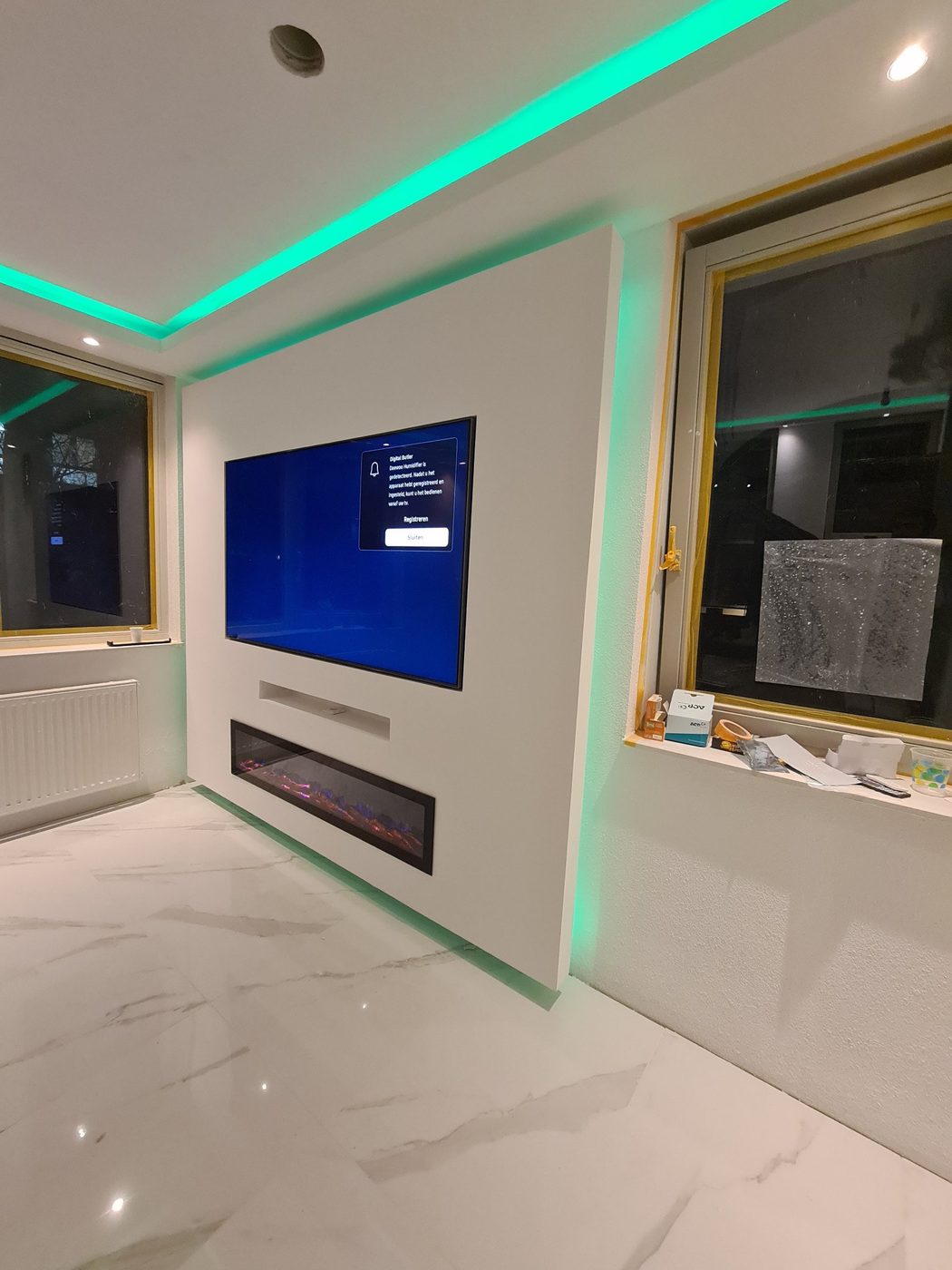 Koof met LED-verlichting boven een tv-wand met sfeerhaard