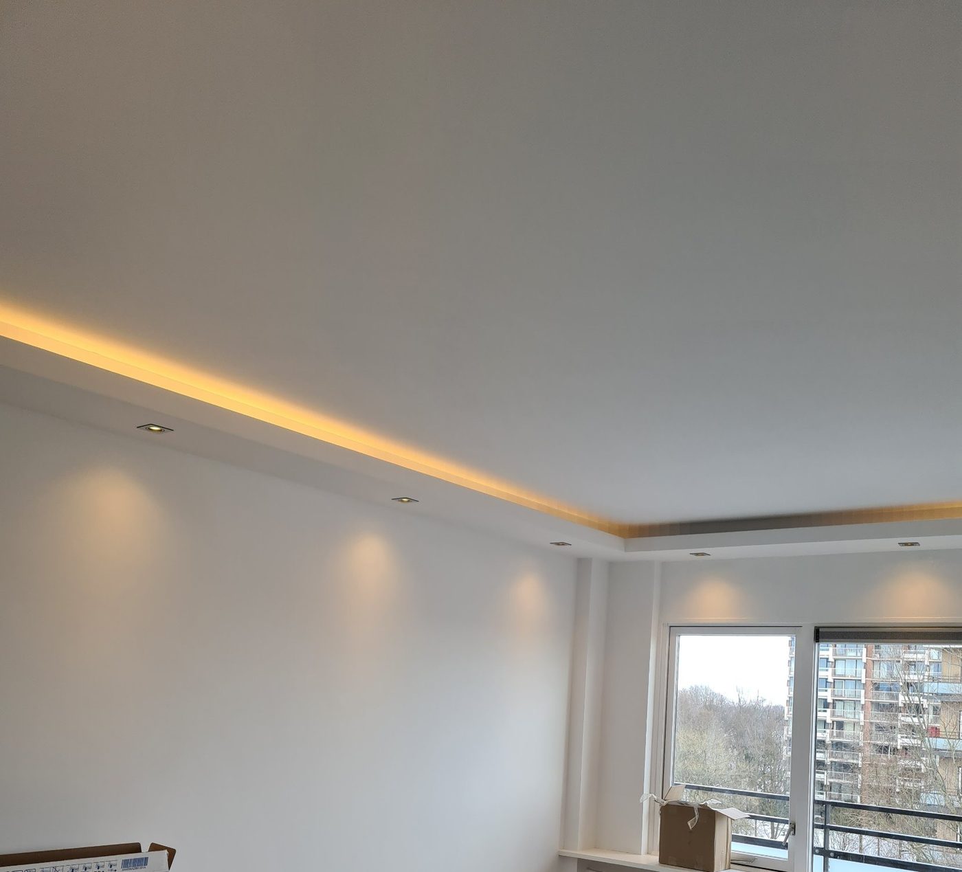 Koof met LED-verlichting langs het plafond in een lichte woonkamer