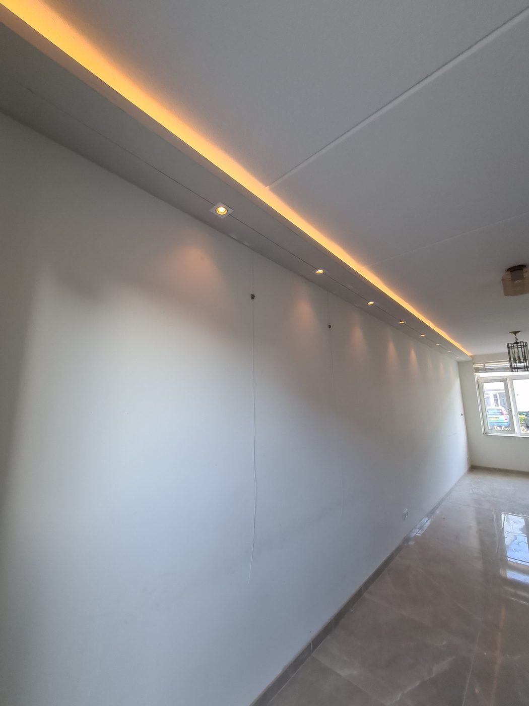 Lange koof met LED-verlichting en spots langs de wand