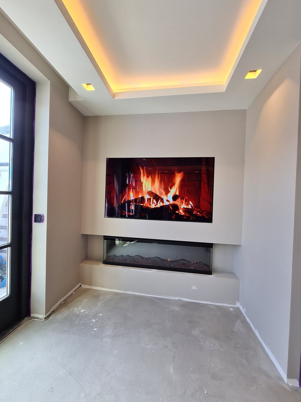 Koof met LED-verlichting boven een tv-wand met sfeerhaard