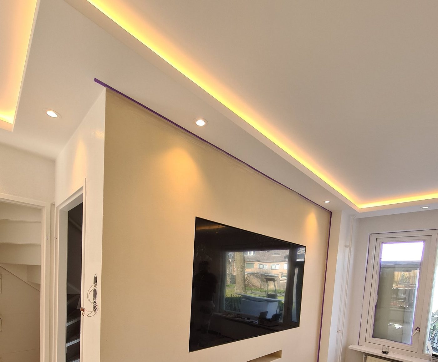 Koof met LED-verlichting boven een gestucte tv-wand