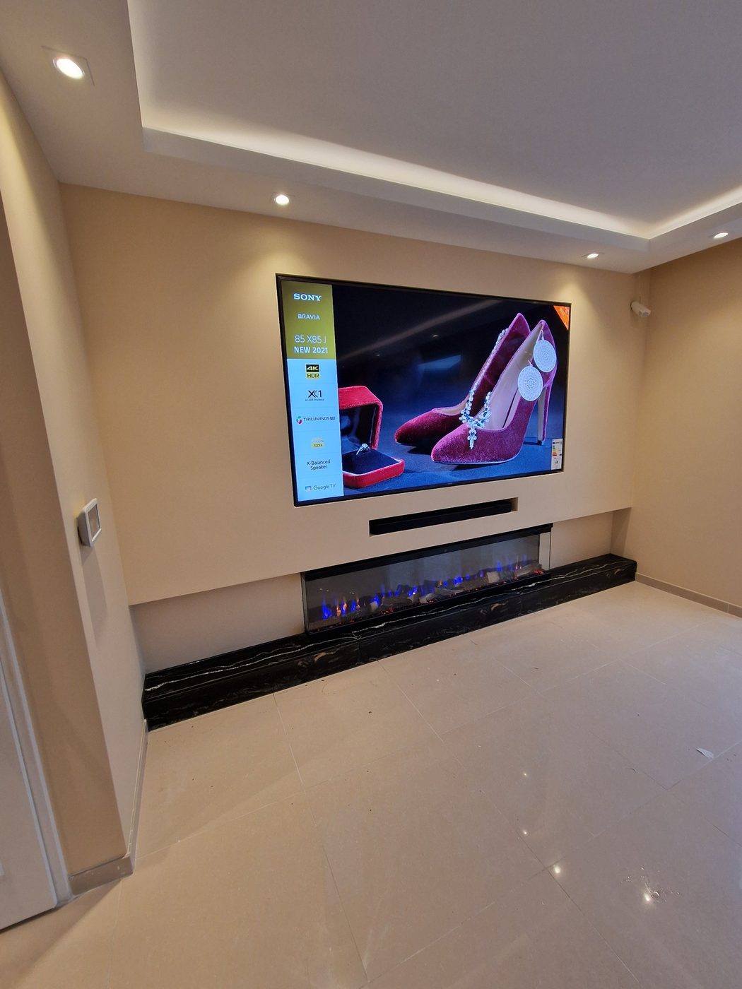 Koof en verlaagd plafond laten maken in Utrecht 5 Verlaagd plafond met LED-koof en spots boven een tv-wand met sfeerhaard