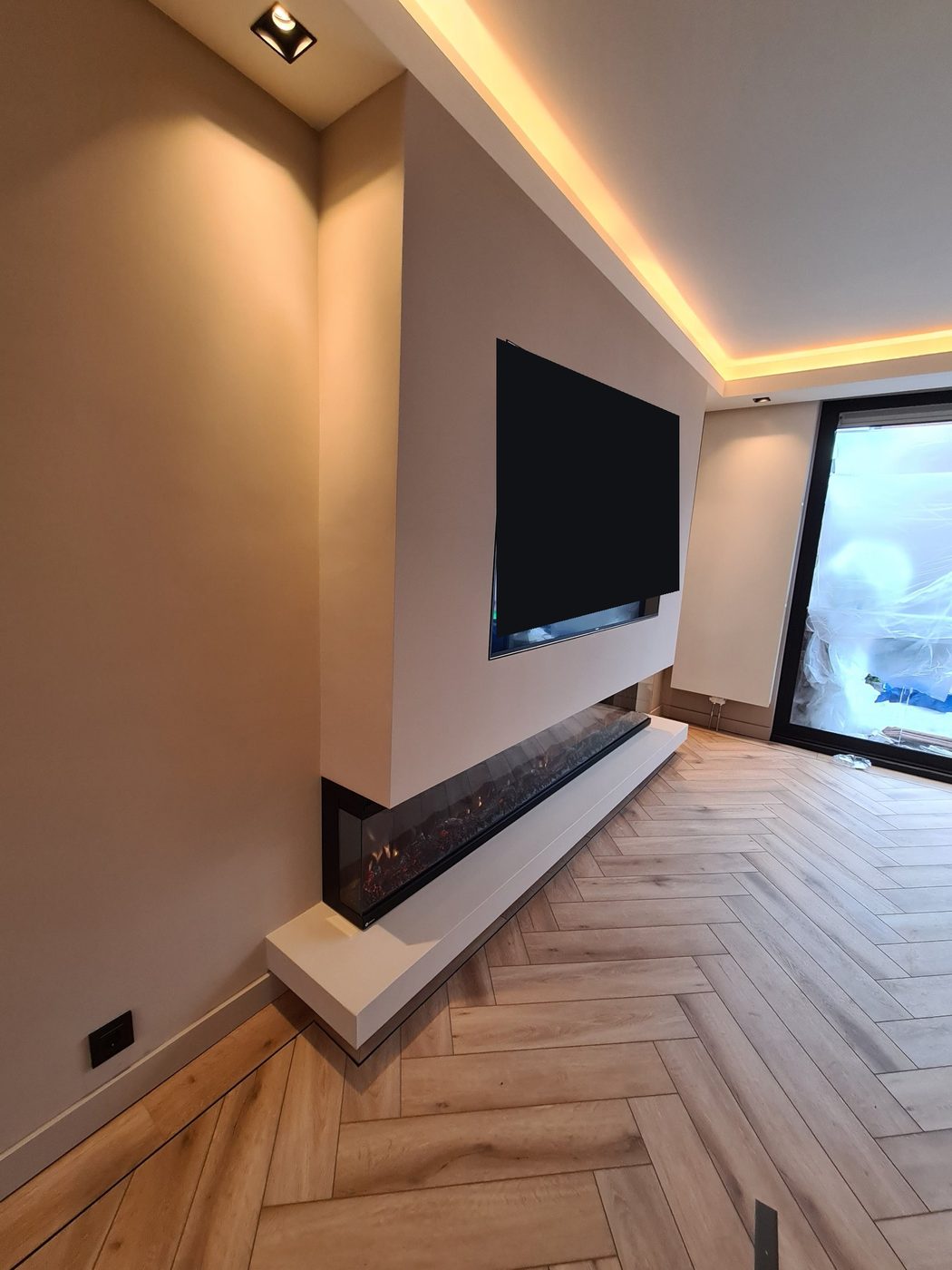 Koof met LED-verlichting boven een tv-wand met sfeerhaard