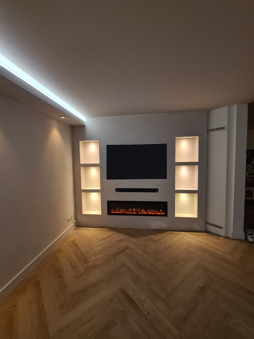 Woonkamer met LED-koof, tv-wand, verlichte nissen en sfeerhaard