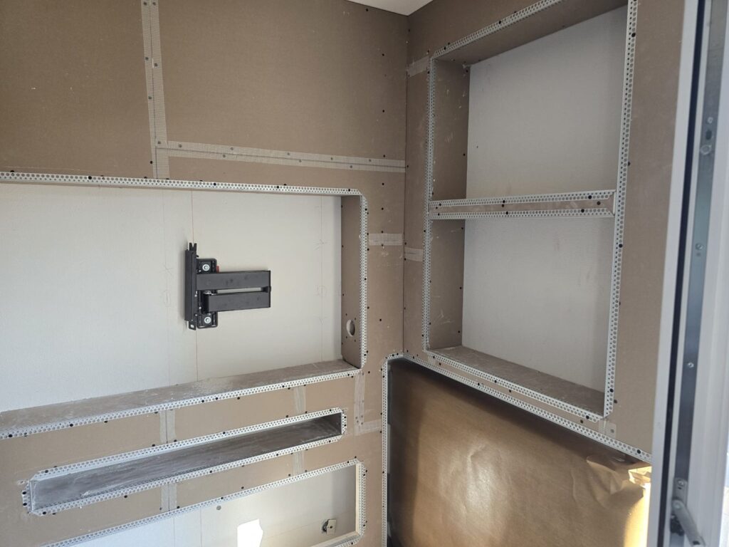Detail van de tv-nis met beugel en de hoeknissen boven de radiator in Maastricht