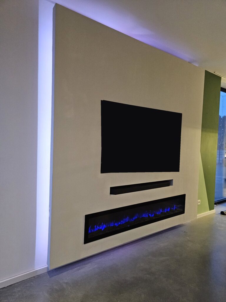 Witte cinewall met extra brede sfeerhaard en kleur-led in Sittard-Geleen 4 Zijaanzicht van de cinewall in Sittard-Geleen met led-gloed achter de wand