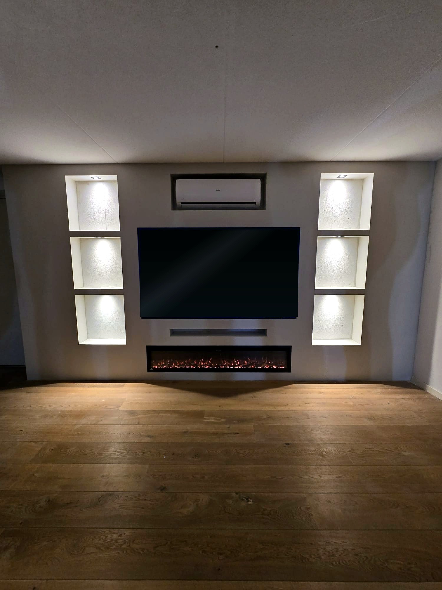 Cinewall van 5 meter met 75 inch tv, sfeerhaard en verlichte nissen in Sneek 1 Cinewall in Sneek van 5 meter breed met 75 inch tv, zes verlichte nissen, soundbar-vak en sfeerhaard, gebouwd om de bestaande airco heen