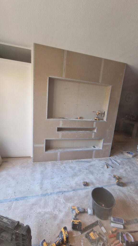 Vrijstaande cinewall met sfeerhaard en soundbar-vak in Sneek 3 Cinewall in Sneek in aanbouw: gipsplaat met uitsparingen voor tv, soundbar en haard